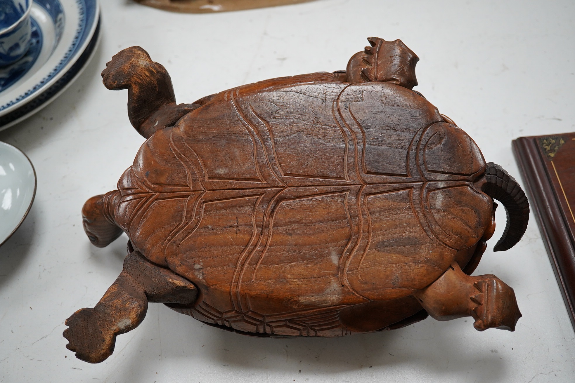 A late 19th century/early 20th century carved walnut box in the form of a tortoise, the shell opening to reveal a compartment, 29cm wide. Condition - fair, tail re-glued